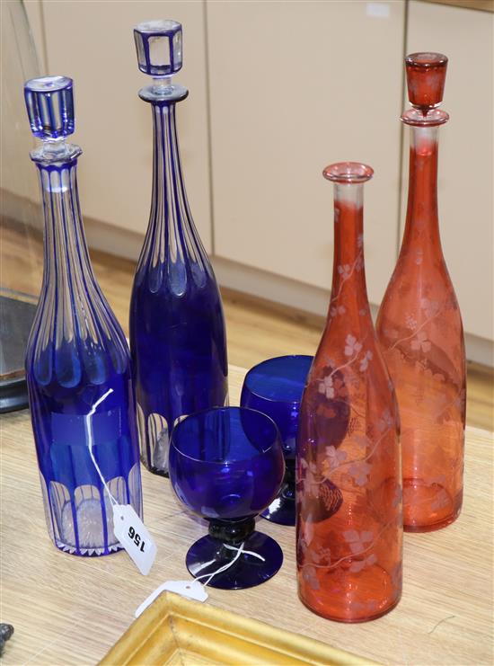 Two blue overlay glass decanters and stoppers, two ruby flask glass decanters and a pair of blue glass goblets,